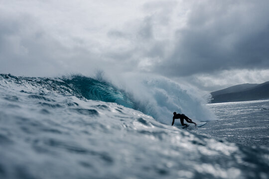 Surfer moving through the tube of a wave under a sky with dense clouds