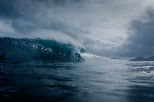 Surfer traveling inside the tubular section of a huge breaking wave
