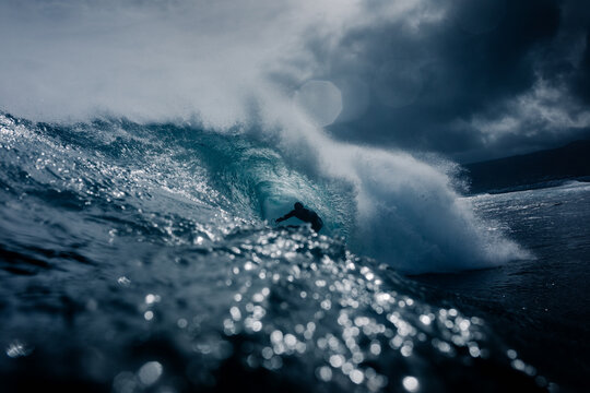 Wide view of professional surfer passing through the barrel of a wave