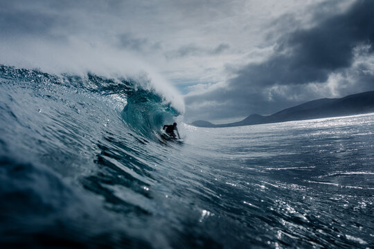 Pro surfer riding deep inside the barrel of a towering wave 
