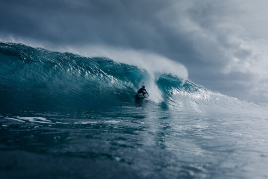Professional surfer moving inside the hollow barrel of a massive wave