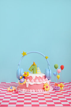 Cute pink birthday cake with number one candle and headphones