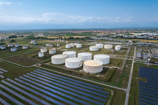 Aerial view of the hydrocarbon and LPG storage facility with large white tanks and solar panel arrays in Volpiano, Piemonte, Italy.