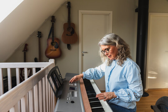 Woman playing electronic keyboard at home with guitars in background