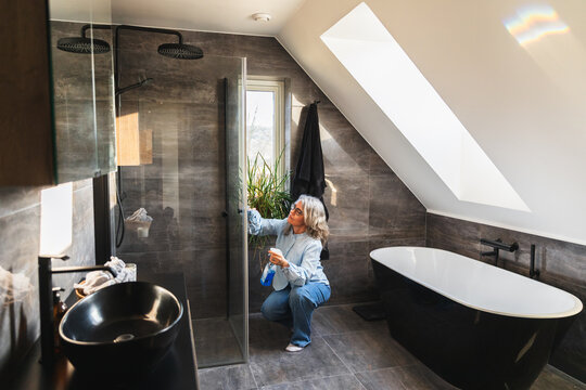 Person cleaning glass shower door in a luxury modern bathroom
