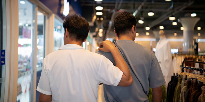 Gay couple shopping in mall man putting arm around partner's shoulder
