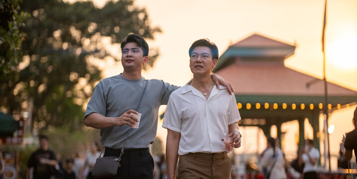 Gay couple enjoying date walking outdoors looking away at sunset