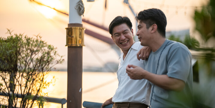 Gay couple enjoying sunset, man laughing cheerfully with partner