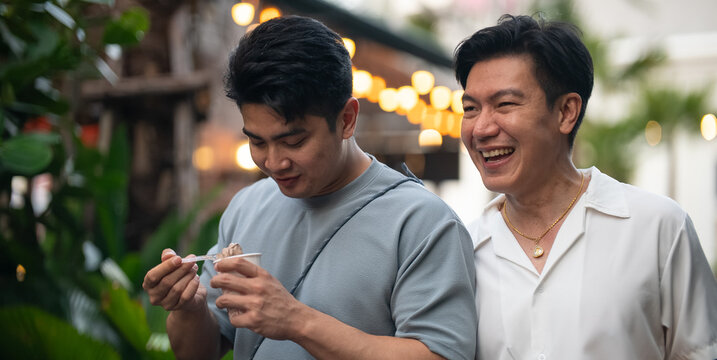 Couple enjoying street food, man eating while a date walking