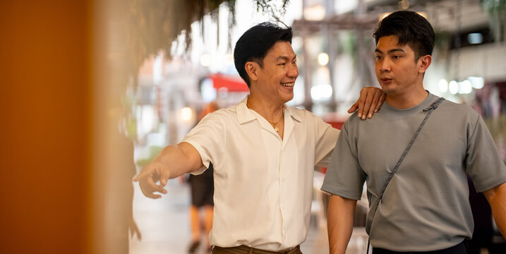 Asian gay couple enjoying shopping together, walking in modern mall