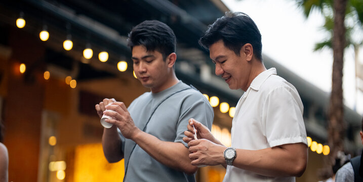 Gay couple enjoying ice creams outdoors smiling and sharing romance