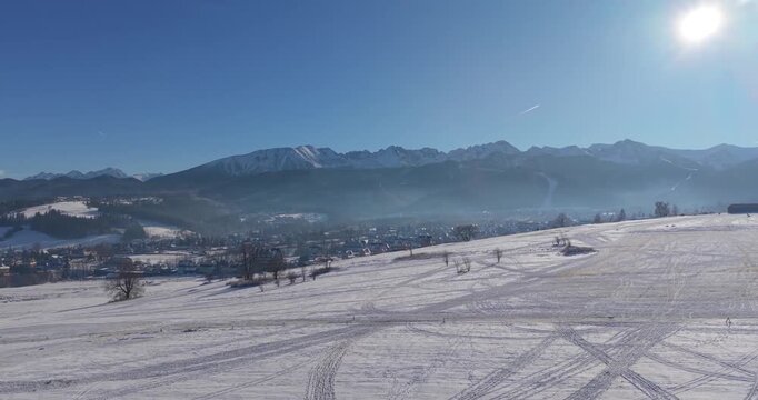 Winter aerial panorama of the Tatra Mountains and snow covered fields under clear blue sky