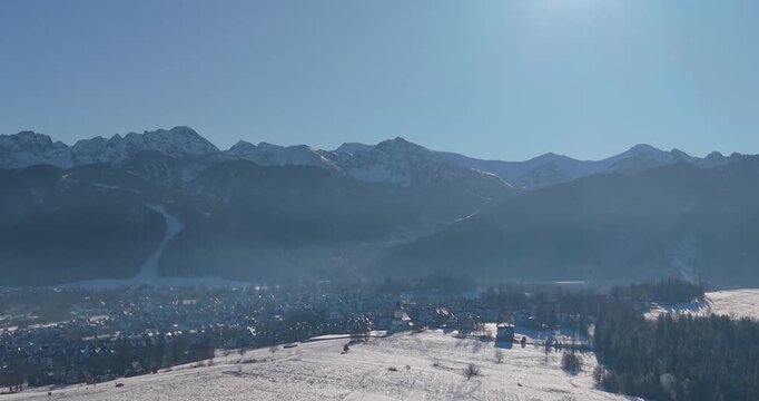 Winter aerial panorama of the Tatra Mountains and snow covered fields under clear blue sky