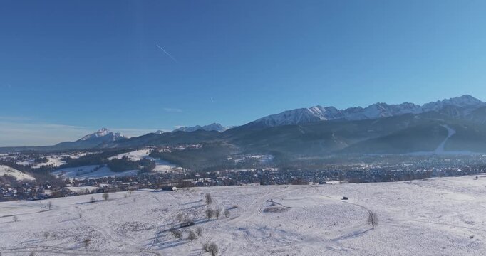 Winter aerial panorama of the Tatra Mountains and snow covered fields under clear blue sky