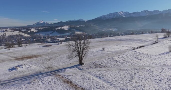 Winter aerial panorama of the Tatra Mountains and snow covered fields under clear blue sky