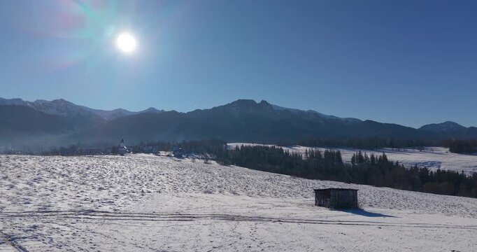Winter aerial panorama of the Tatra Mountains and snow covered fields under clear blue sky