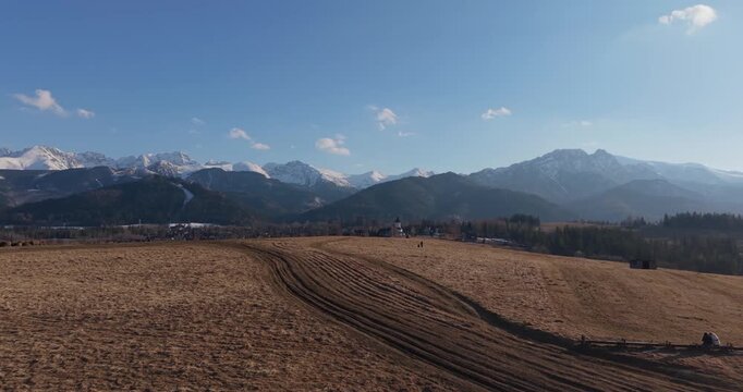 Spring aerial view of the Tatra Mountains with snowy peaks and meadow foreground
