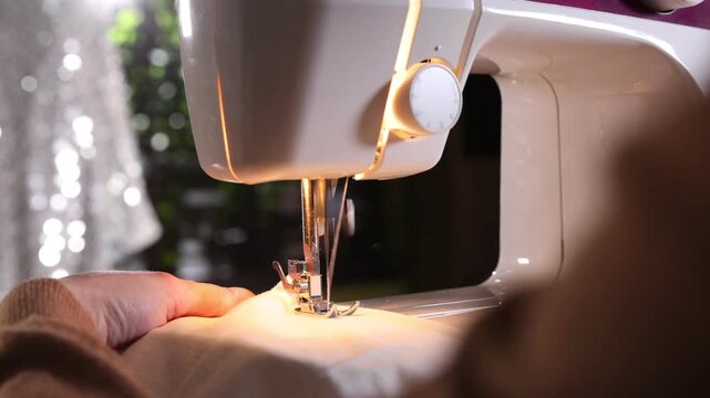 Woman sewing fabric with professional machine in workshop, closeup