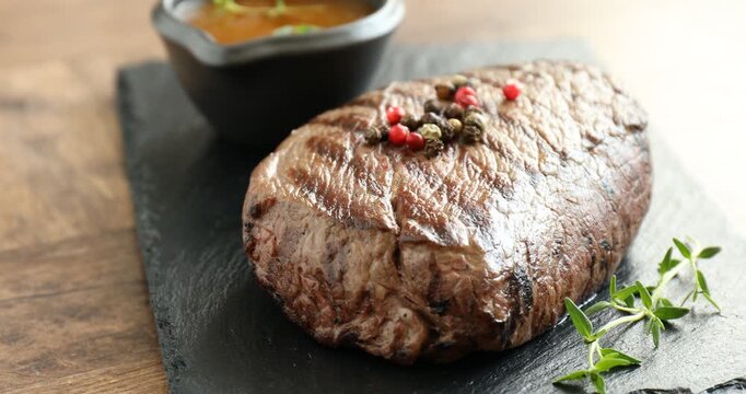 Tasty beef steak served on wooden table, spinning