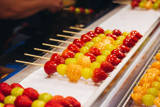 Ddalgi Satang, Fruit Hard Candy on stick skewers, candied strawberry, grape and tangerine in hardened sugar, traditional street food selection, Seoul, South Korea, local tasty dishes on night market