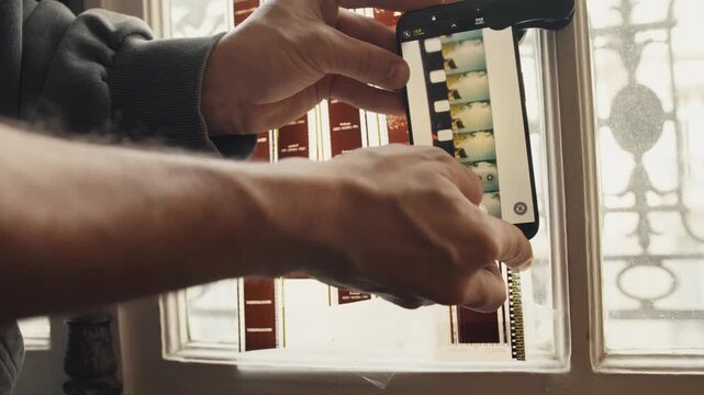 Photographer scanning old film negatives with smartphone