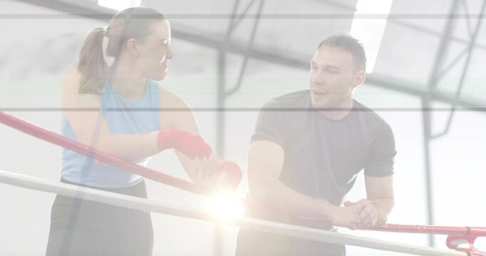 Preparing for training, boxer adjusting red wraps while trainer coaching, skylight flare appearing