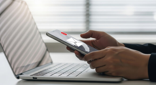Mobile email notification concept, unread message alert on smartphone screen, user checking inbox on device beside laptop, digital communication, business workflow and productivity in modern workplace