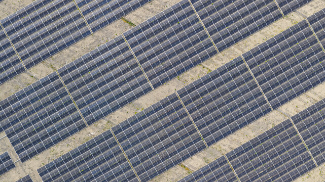 Aerial view of Zonnepark Braambergen with rows of solar panels arranged in geometric patterns on sandy ground in Almere, Flevoland, Netherlands.