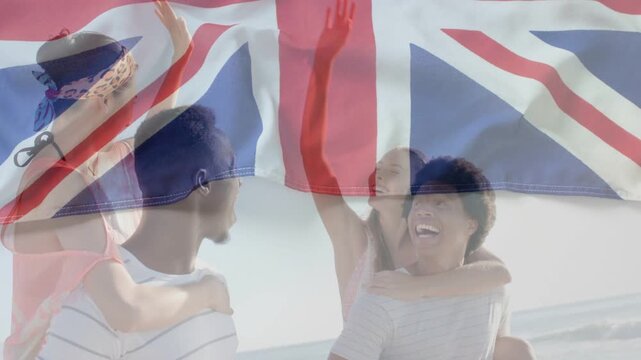 Two men giving piggyback rides on beach lifting arms sparking UK flag overlay, laughing for travel