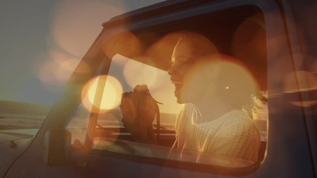 Adult woman raising camera in truck, sunset causing photography with bokeh flares intensifying