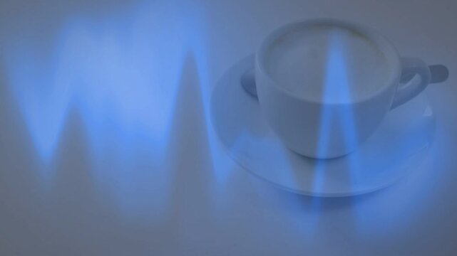 White cup, saucer on pale table, blue wave entering left making light bands on cup, ads
