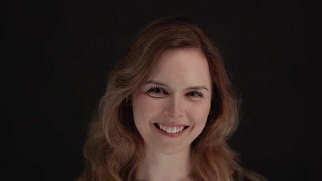 Authentic joy and happiness a close-up shot of a woman smiling and laughing against a black background.