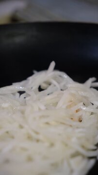 Chopped vegetables, daikon mooli,  garlic frying in olive oil on a pan, close up. Сast iron skillet, Food in motion, process . Cooking, restaurant cookery
