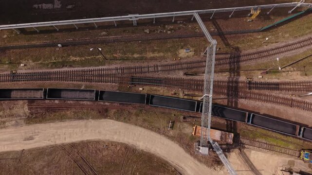 Aerial Freight Train In Warszawa Showing Long Black Wagons On Curved Rails, Coupling Points And Trackbed Freight Operator Monitors Carriage Movement And Cargo Flow Under Clear Daylight