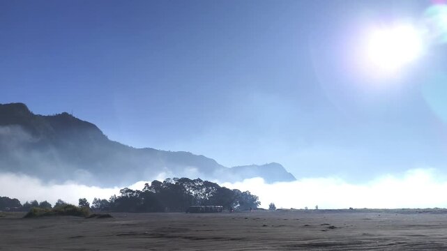 Scenic morning light over expansive desert plain with mist clouds and mountain silhouette, high contrast sky and natural textures, ideal for cinematic footage, travel inspiration, nature storytelling