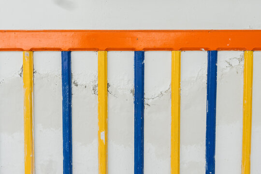 Pared con listones verticales en azul y amarillo con borde naranja y textura desgastada