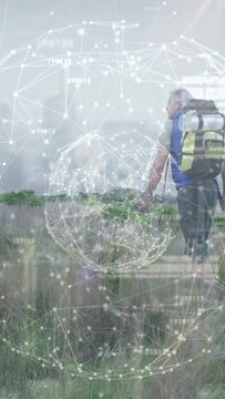 Vertical video: Hiker bending checking grass, activating tech globe overlay while walking plain