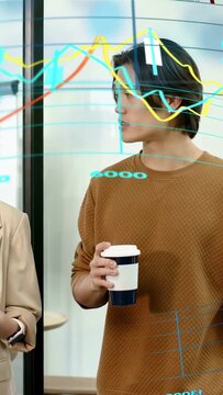 Vertical video: Man holding cup reviewing as woman tapping tablet showing AR charts 4000-8000 tech