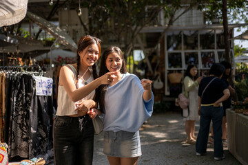 Naklejka premium Young women friends pointing enjoying street market shopping