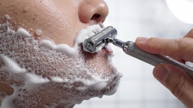 Close-up of man shaving with safety razor.