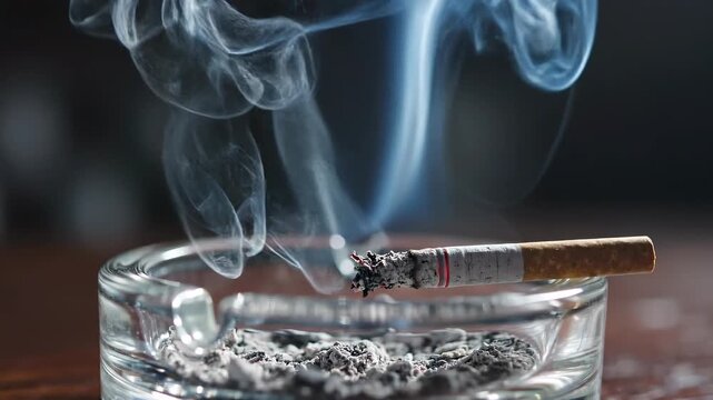 A cigarette smoldering in an ashtray with smoke rising.