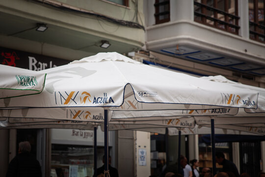 VALENCIA, SPAIN - APRIL 11, 2025: El Aguila beer branding printed on large terrace umbrellas outside a bar in Valencia, Spain. Part of Heineken International, El Aguila is a spanish brand of beer.