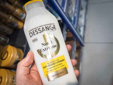 PARIS, FRANCE - MARCH 4, 2026: Hand holding a Dessange Paris shampoo bottle inside a supermarket in Paris, France. Dessange is a French hairdresser having a chain of beauty salons accross the world.