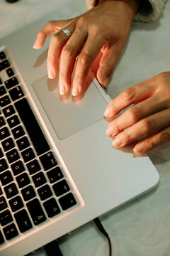 Close-up of hands using a laptop trackpad, soft warm lighting, minimal workspace, focused digital interaction and productivity at home.
