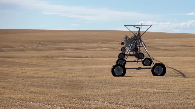 Center pivot irrigation system in open Alberta farm field showing agricultural equipment in prairie landscape