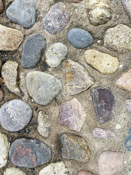 Surface of natural stones laid in a pattern on a pathway during daylight