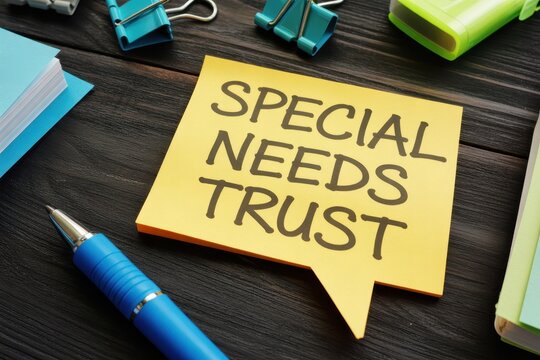 Special Needs Trust message written on a yellow sticky note on a dark wooden office desk