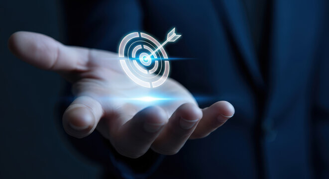 Hand holding illuminated target with arrow in center Goal oriented business strategy and concept of aiming for success by implementing plans