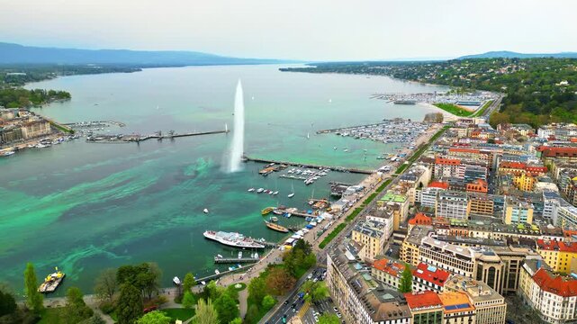 Aerial view of Jet d'Eau water fountain on Lake Geneva with city buildings and boats.
