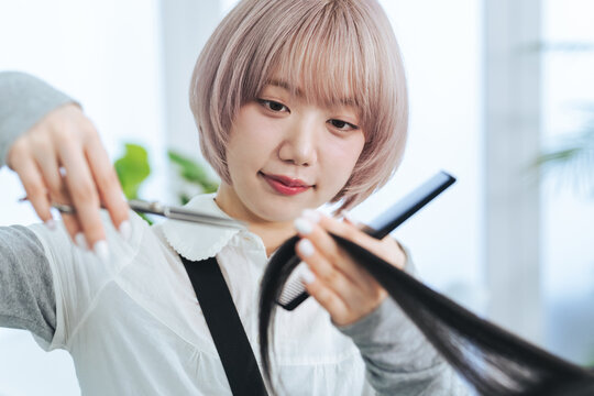 ヘアカットするハイトーンヘアの女性スタッフ